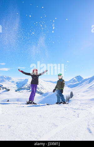 Portrait von Skifahren Jugendmädchen und Bruder werfen Pulverschnee in den Schweizer Alpen, Gstaad, Schweiz Stockfoto