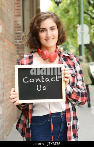 Junge schöne Frau Holding Tafel mit Text 'Kontakt'. Im Freien. Stockfoto