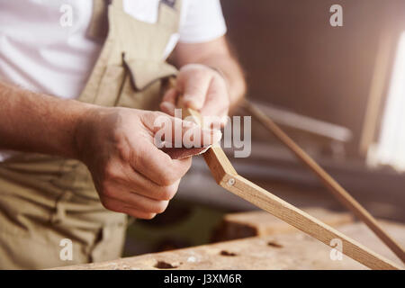 Die Hände der männlichen Tischler schleifen Rahmen an Workbench Stockfoto