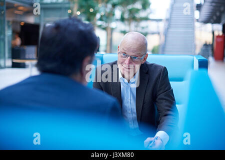 Blick über die Schulter der Unternehmer bei der Sitzung im Atrium Stockfoto