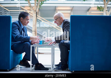 Zwei Geschäftsleute in Diskussion Sitzung im Atrium Sessel Stockfoto