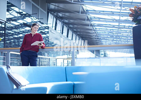 Geschäftsfrau lesen Papierkram im Büro atrium Stockfoto