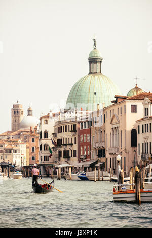 Klassische Ansicht von einer Gondel schweben auf einem der vielen Kanäle in Venedig, Italien. San Simeone Piccolo ist die Kirche mit der grünen Kuppel. Stockfoto