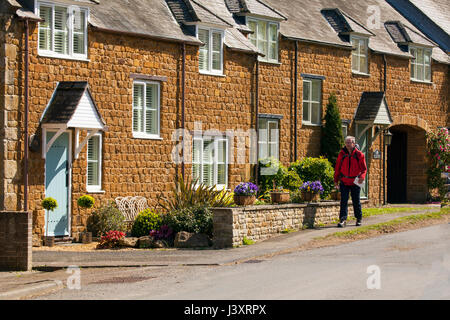 Mann trägt rot Wandern zu Fuß durch das Dorf Lyddington in Englands kleinste Grafschaft Rutland Jacke Stockfoto