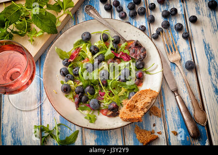 Gesunder Salat mit Rucola und Blaubeeren auf einen Tisch im Freien. Stockfoto
