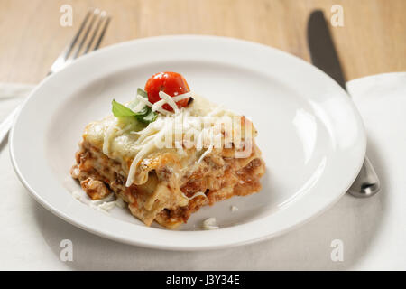 hausgemachte Lasagne Teil auf weißen Teller auf Holztisch Stockfoto