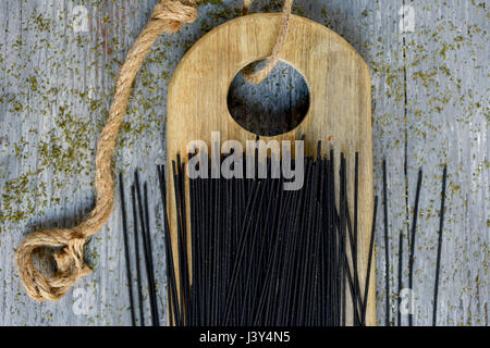 ein Haufen von rohem schwarze Spaghetti auf ein Schneidbrett aus Holz, platziert auf einem grauen rustikalen Holztisch Stockfoto