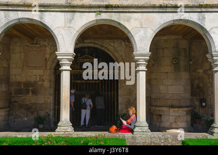 Frau, die Buch liest, Ansicht einer Frau mittleren Alters, die ein Buch liest, während sie allein in einem Kathedralenkloster in Portugal sitzt. Stockfoto