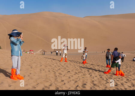 Dunhuang, China - 8. August 2012: Touristen fotografieren in den Dünen rund um die Stadt Dunhuang in der alten Seidenstraße in China. Stockfoto