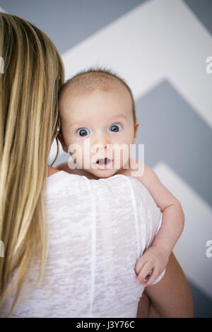 Über die Schulter-Porträt von niedlichen Baby Boy in Mutters Armen Stockfoto