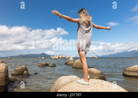 Rückansicht des Mädchens balancieren auf Felsen auf dem Seeweg Stockfoto