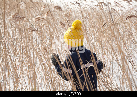 Junge zu Fuß durch lange Wiese, im tief verschneiten Landschaft, Rückansicht Stockfoto