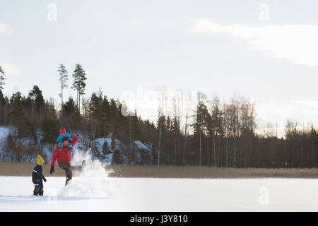 Vater und zwei Söhne, die Narren laufen, etwa durch Schnee bedeckte Landschaft Stockfoto