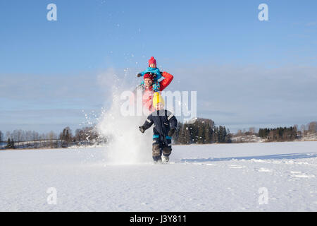 Vater und zwei Söhne, die Narren laufen, etwa durch Schnee bedeckte Landschaft Stockfoto