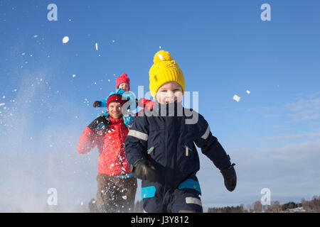 Vater und zwei Söhne, die Narren laufen, etwa durch Schnee bedeckte Landschaft Stockfoto