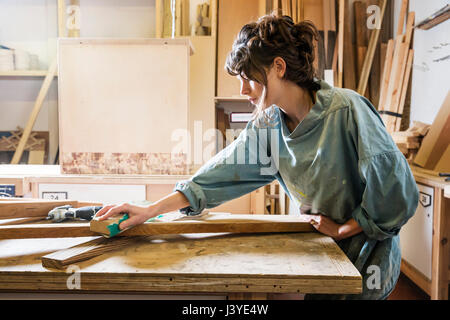 Junge Frau Schleifen Holz in einem workshop Stockfoto