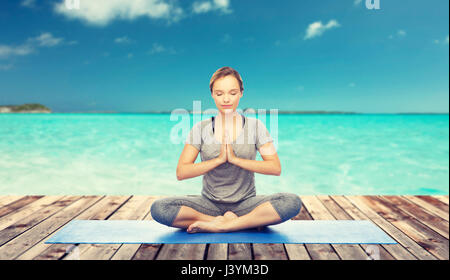 Frau macht Yoga Meditation in Lotus Pose auf Matte Stockfoto