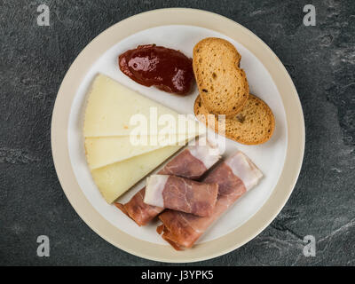 Auswahl an Tapas mit Tomaten Chutney auf einem schwarzen Fliesen-Hintergrund Stockfoto