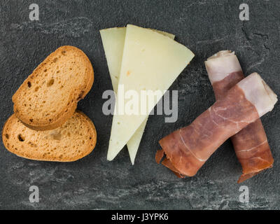 Auswahl an Tapas mit Tomaten Chutney auf einem schwarzen Fliesen-Hintergrund Stockfoto