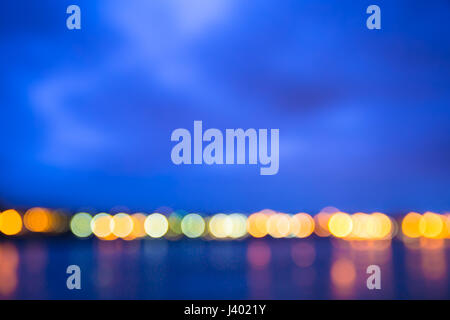 Horizont mit Kreis Bokeh Lichter verschwimmen in der Nacht über Fluss Stockfoto