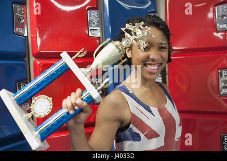 Eine junge Frau mit einer Trophäe in Fornt des roten und blauen Schließfächer. Stockfoto