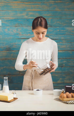 Haus Frau trägt Schürze machen. Schritte der Herstellung Kochen Schokolade Kuchen. Teig mischen Zutaten vorbereiten Stockfoto