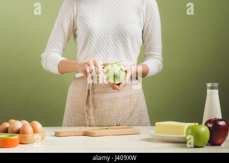 Haus Frau trägt Schürze machen. Schritte der Herstellung Kochen Apfelkuchen. Grünen Apfel schneiden. Stockfoto