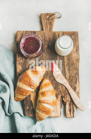 Frisch gebackene Croissants mit Himbeermarmelade und Milch in der Flasche Stockfoto