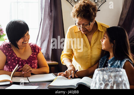 Mutter und Großmutter helfen Mädchen bei den Hausaufgaben Stockfoto