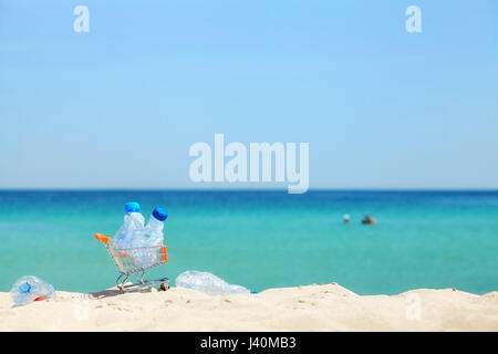 Miniatur-Einkaufswagen mit leeren Plastikflaschen, die Links von Touristen auf einem tropischen Strand, Umweltverschmutzung Konzept Bild, selektiven Fokus. Stockfoto