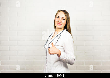Glücklich lächelnd Ärztin zeigt Daumen hoch Hand unterzeichnen Geste, im Büro, mit leeren Exemplar für Slogan oder Text annoncieren. Gesundheitswesen, Medizin, Labor Beratung und Prüfung Konzept. Stockfoto