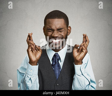 Closeup Portrait junger lustiger Kerl, Geschäftsmann, überqueren die Finger, grau wünschen, in der Hoffnung für beste, Wunder isoliert schwarz Hintergrund. Positiven menschlichen emo Stockfoto