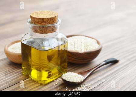 Sesamsamen und Öl in der Flasche auf hölzernen Hintergrund Stockfoto