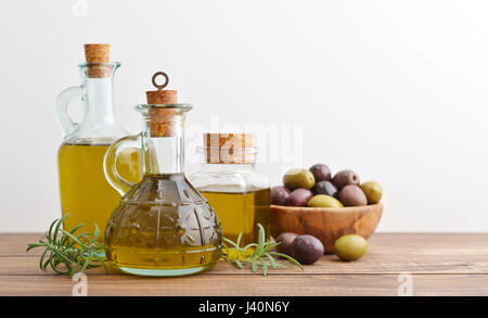 Olivenöl und Beeren sind auf dem Holztisch auf hellem Hintergrund Stockfoto