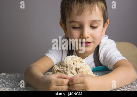 Kleiner Junge ist rohe Pizzateig kneten und eine Umarmung Stockfoto