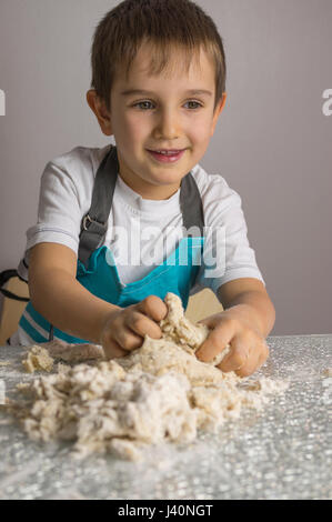 Little Boy ist rohe Pizzateig zu kneten und lächelnd Stockfoto