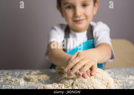 Kleiner Junge rohe Pizzateig zu kneten. Fokus auf Vordergrund. Stockfoto