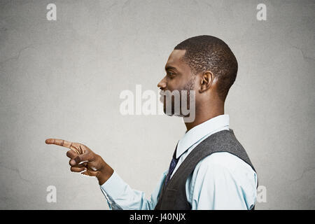 Closeup Portrait Seite Ansicht Profil lächelnder schöner junger Mann zeigte auf Sie mit dem Zeigefinger, isoliert grau hinterlegt. Menschliche Emotionen, Gesichts expr Stockfoto