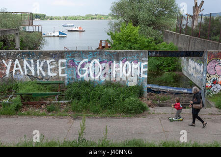 Belgrad, Serbien - 8. Mai 2017: alte Frau und ihre Enkelin, vorbei an einer Wand mit einer Anti-amerikanische Inschrift an der Wand: "Yankees nach Hause gehen" Pictu Stockfoto