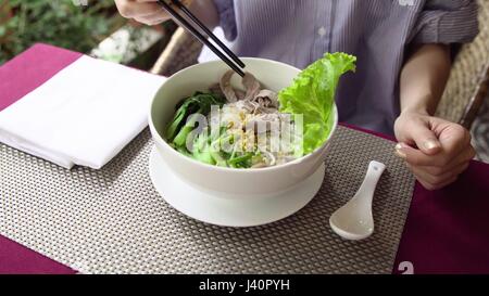 Frau Essen im Restaurant traditionelle Vietnam Pho Bo Rindfleisch Nudelsuppe. Kellner servieren Suppe im Café. 4K Stockfoto