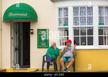 Ein Paar, das im Mai vor dem Brunswick Guest House sitzt und eine Tasse Tee im Weymouth, Dorset UK, serviert Stockfoto