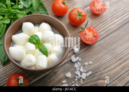 Mozzarella mit Cherry-Tomaten und Basilikum Blätter auf hölzernen Hintergrund Stockfoto