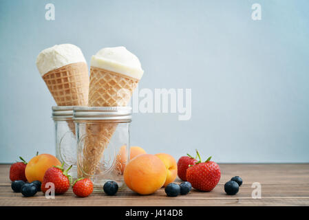 Eis in den Zapfen mit frischen Beeren auf blauem Hintergrund Stockfoto