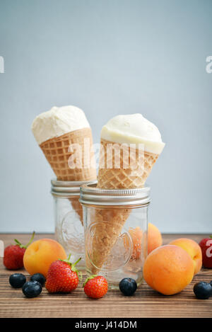 Eis in den Zapfen mit frischen Beeren auf hölzernen Hintergrund Stockfoto