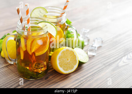 Eistee mit frischen Zitronen und Minze auf hölzernen Hintergrund Stockfoto