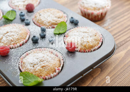 Nur gebackenen Muffins In Backformen mit frischen Beeren closeup Stockfoto