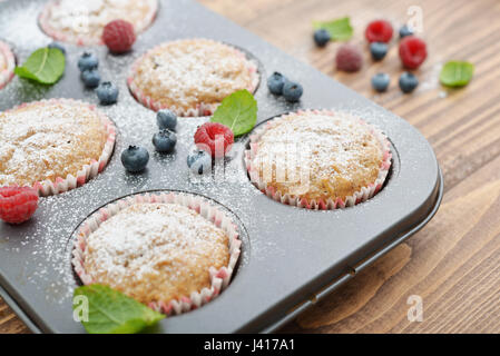 Nur gebackenen Muffins In Backformen mit frischen Beeren closeup Stockfoto
