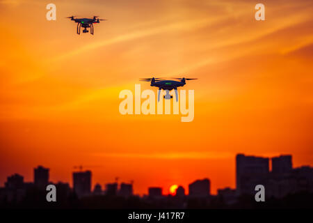 Zwei moderne Fernbedienung Luft Drohnen fliegen mit Action-Kameras in dramatischen orange Sonnenuntergang sk Stockfoto