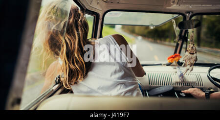 Frau in einem Auto sitzen legte Kopf aus Fenster Wind weht ihr Haar Stockfoto