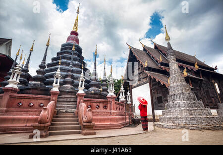 Frau mit roten traditionelle Thai Regenschirm betrachtet man schwarzen Tempel Wat Phan Tao gemacht aus Holz in Chiang Mai, Thailand Stockfoto